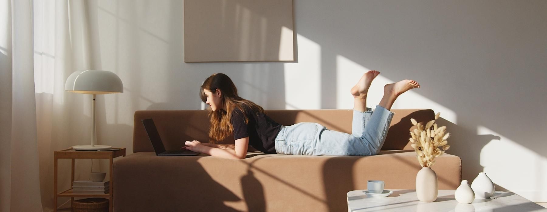 a person lying on a couch with a laptop