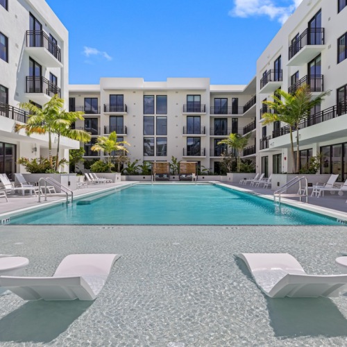 Resort-style swimming pool pool in a courtyard with lounge chairs